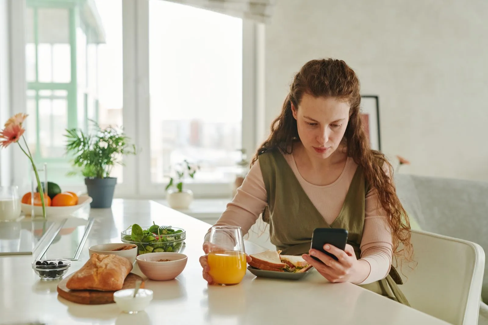Pregnant woman at her kitchen table checking her phone